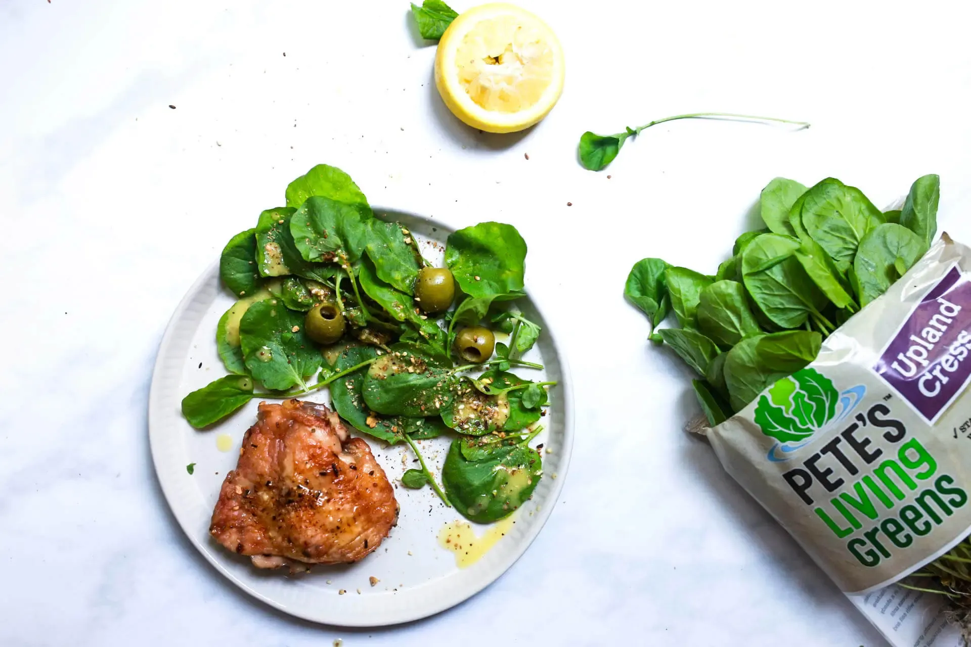 Photo of plate with watercress salad, chicken, and olives
